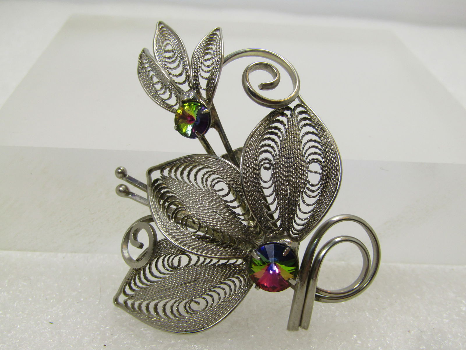 Vintage Silver Tone Filigree Leaf Brooch AB Rhinestones, 1960's-1970's: Vintage Silver Tone Filigree Leaf Brooch AB Rhinestones, 1960's-1970's. This has domed leaves that curve down on top and buttom and are raised in the center. There are two clusters of leaves with coil
