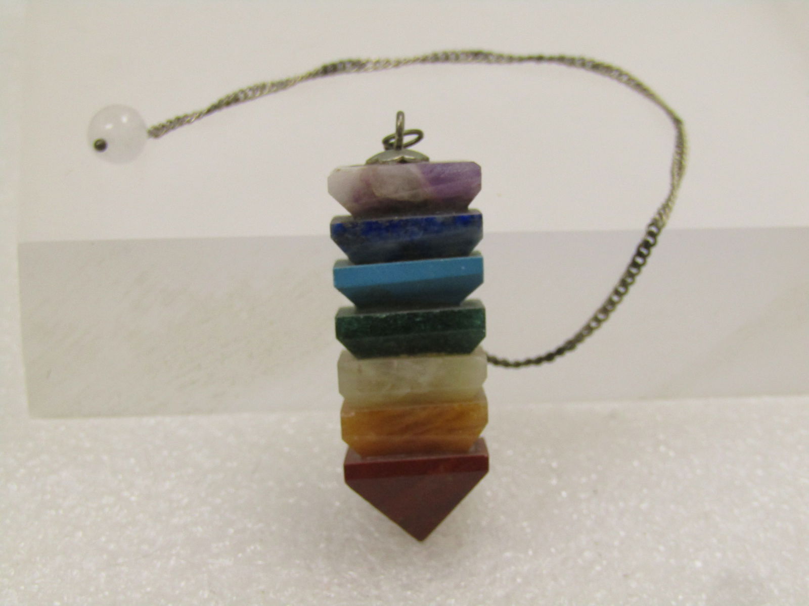 Stacked Pyramid 7 Chakra Pendulum, 1980's-1990's: Stacked Pyramid 7 Chakra Pendulum, 1980's-1990's. The pendulum has seven semi-precious stones in amethyst, citrine, jadeite and more. It is appx. 1.75" long and 5/8" square. It has a 6.5" chain