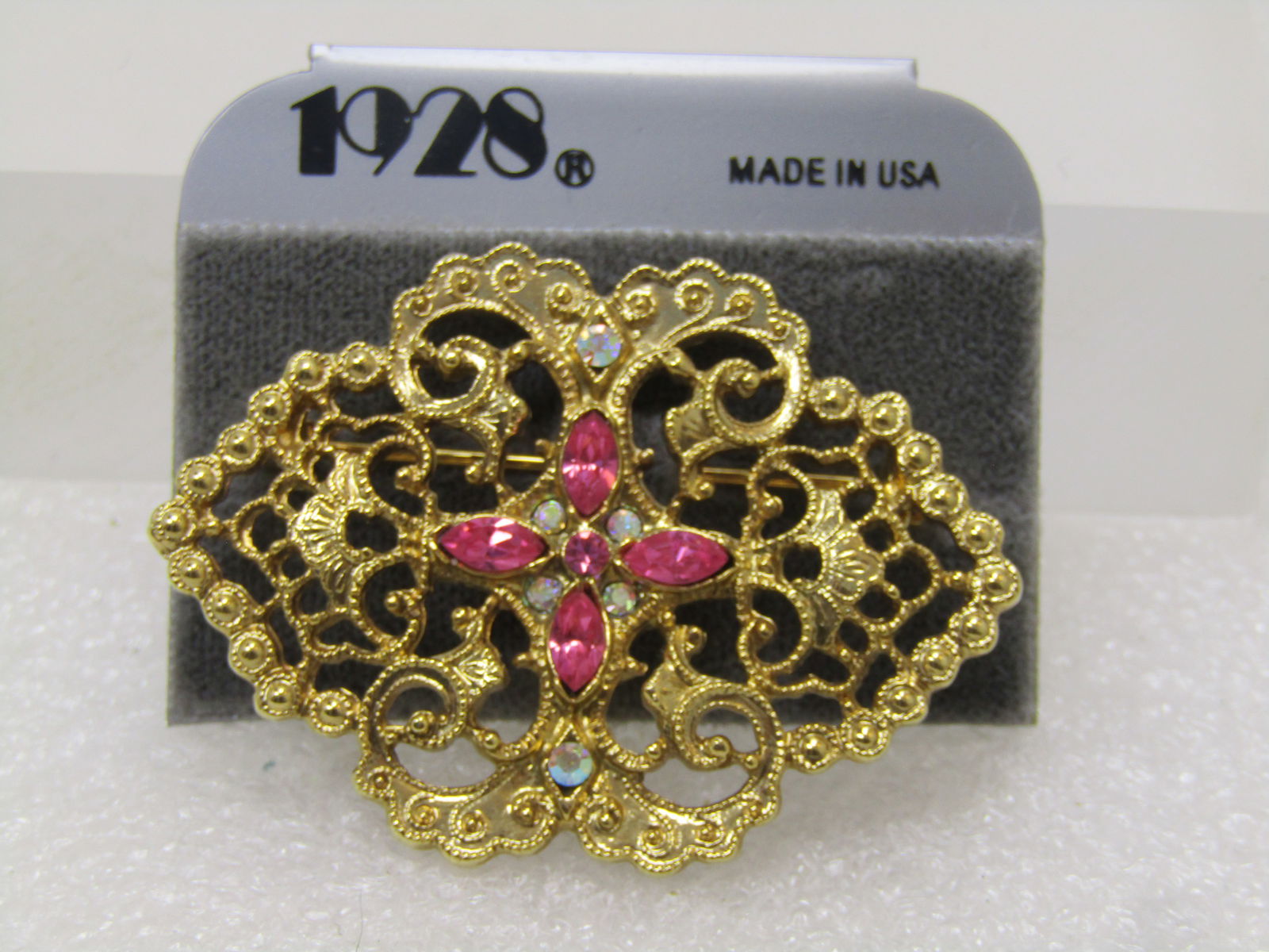 Vintage 1928's Pink Rhinestone Brooch, Victorian Themed, On Original Card, 1980's.: Vintage 1928's Pink Rhinestone Brooch, Victorian Themed, On Original Card, 1980's. Filigree gold tone design with a center of pinke marquise rhinestones in a north; south; east; and, west position and
