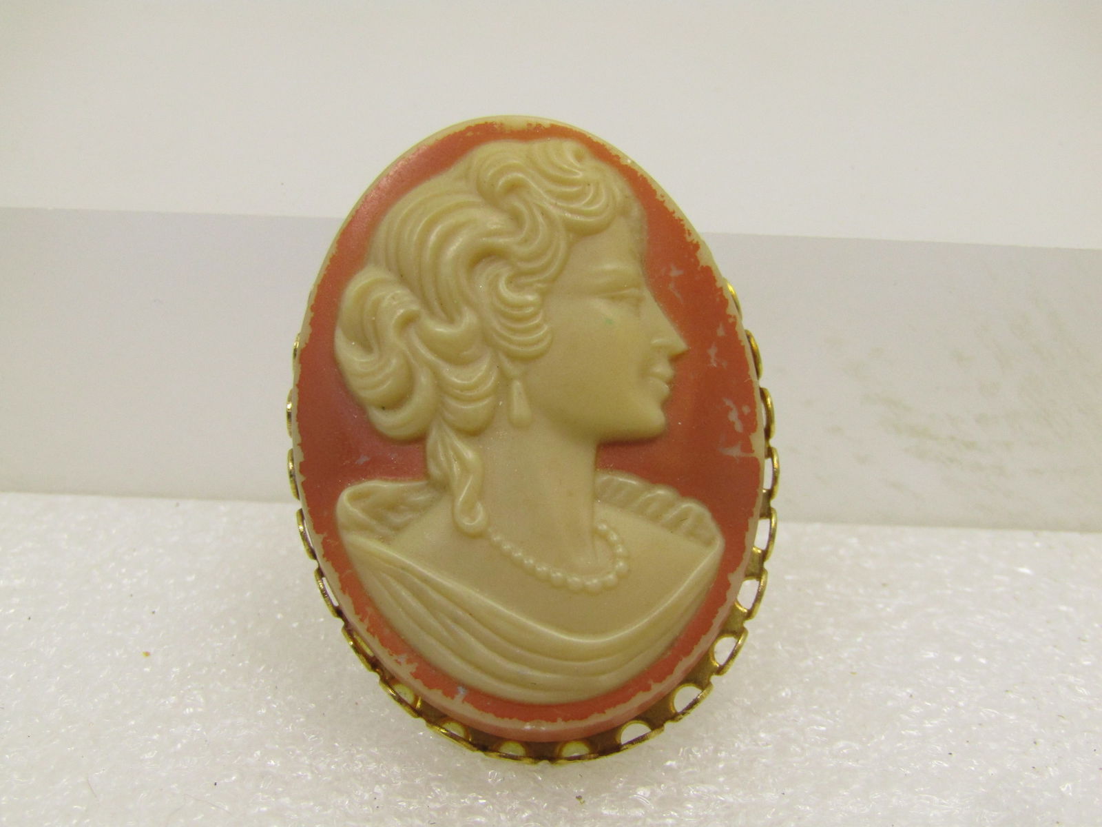 Vintage Cameo Brooch, 1950's-1960's: Vintage Cameo Brooch, 1950's-1960's. Gold tone butterscotch background and off white cameo - woman with pearls. The brooch has an open scalloped bezel. It is appx 1.75" tall and 1.25" wide. Locking cl
