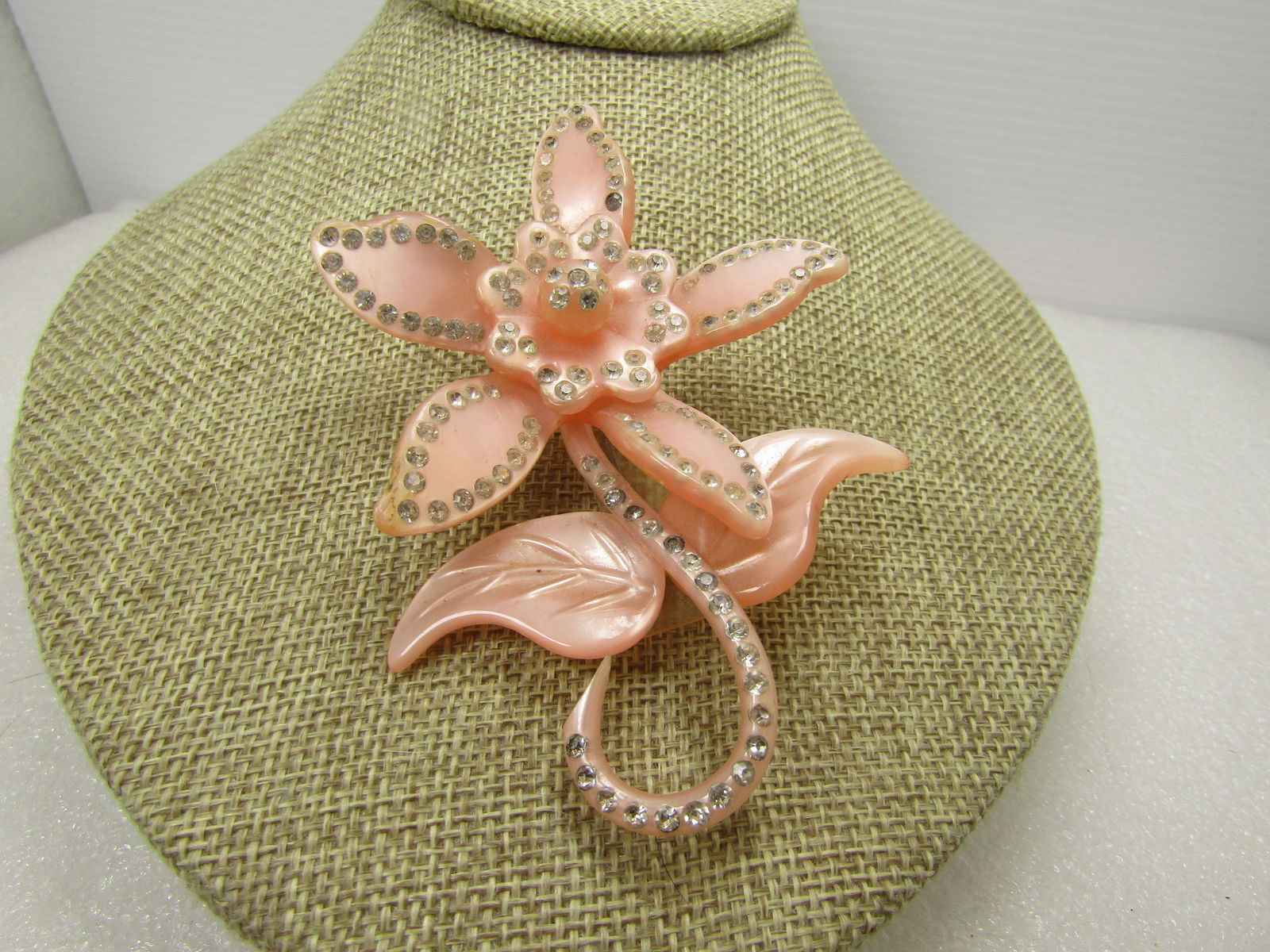 Vintage Pink Celluloid Floral Brooch, Rhinestones, 1940's: Vintage Pink Celluloid Floral Brooch, Rhinestones, 1940's. This has a large blossom, two leaves and a curled stem with clear rhinestones outlining he petals and the stem. It is appx. 3.5" tall and 2.5