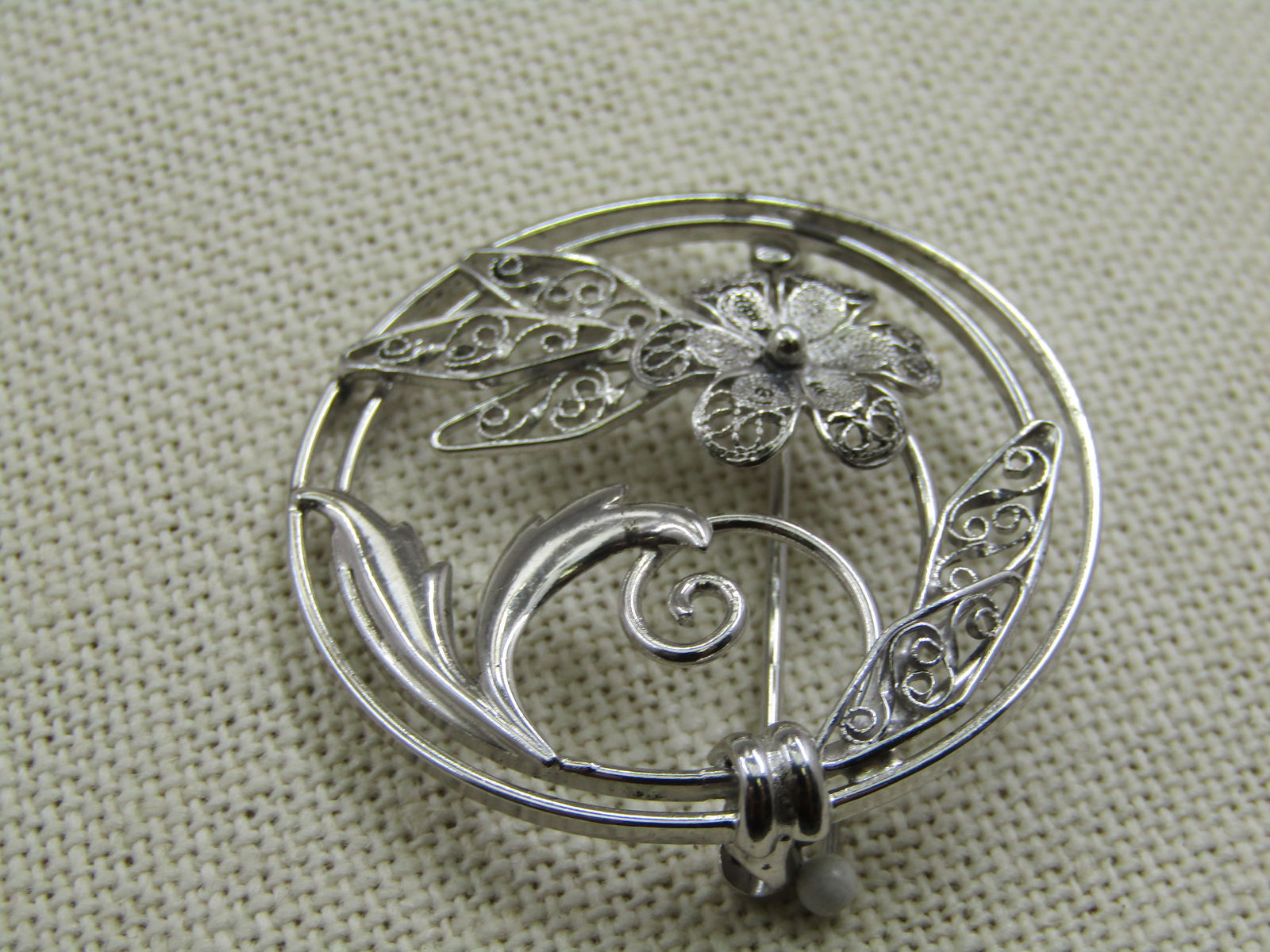 Vintage Sterling Carl Art Floral Filigree Cirlce Brooch: Vintage Sterling Carl Art Floral Filigree Cirlce Brooch - 1-3/8" across. Marked sterling and tested. Weight is appx. 5.43 gr. Floral blossoms and leaves with double framed circle with solid curved lea
