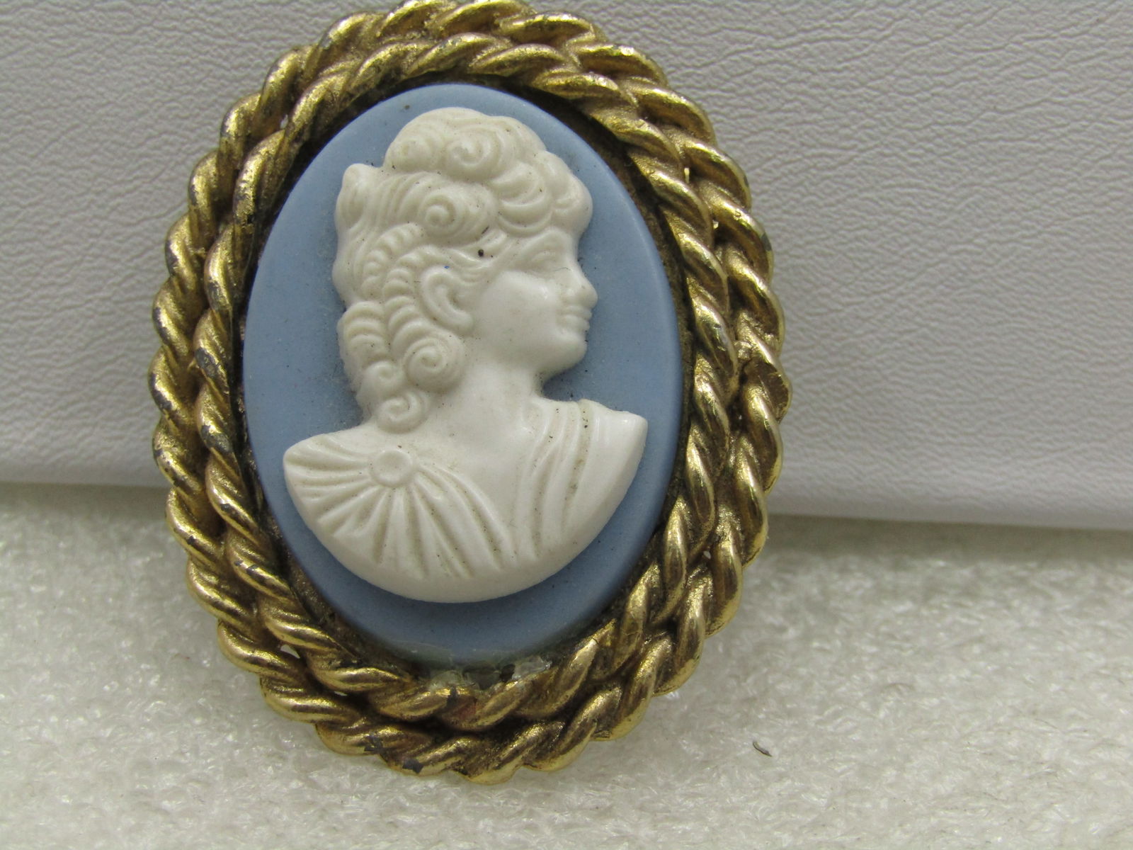 Vintage Blue White Cameo Scarf Clip, 1960's-1980's, Gold Tone: Vintage Blue White Cameo Scarf Clip, 1960's-1980's, Gold Tone. 1.75" tall and 1.25" wide oval. Pressed white plastic cameo image set on a wedgwood blue background, also plastic. Good condition, some l