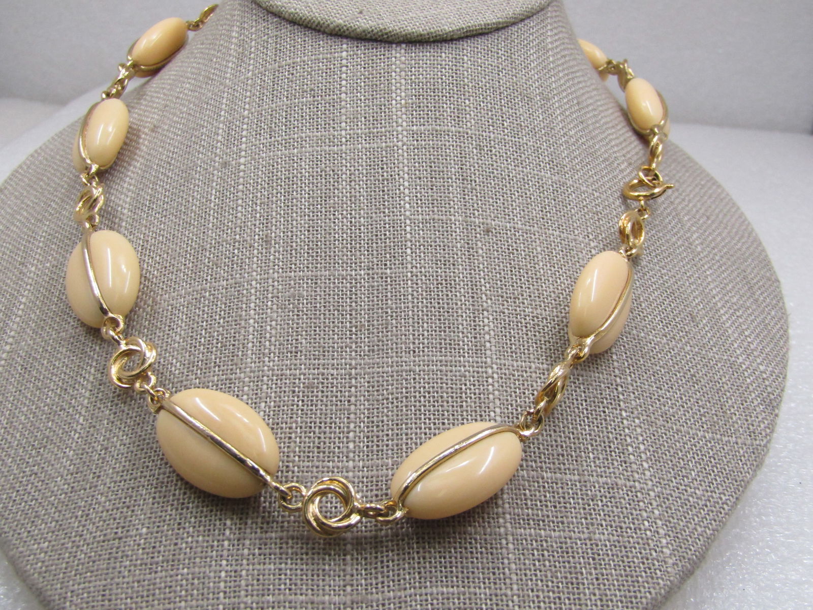 Vintage Cream Lucite Oval Beaded Necklace, Gold Tone Love Knot Link , 22", 1960's-1970's: Vintage Cream Lucite Oval Beaded Necklace, Gold Tone , 22", 1960's-1970's. Each of the 1.25" off cream plastic beads have a gold wrap front and back that connect to a love-knot syle connector link,