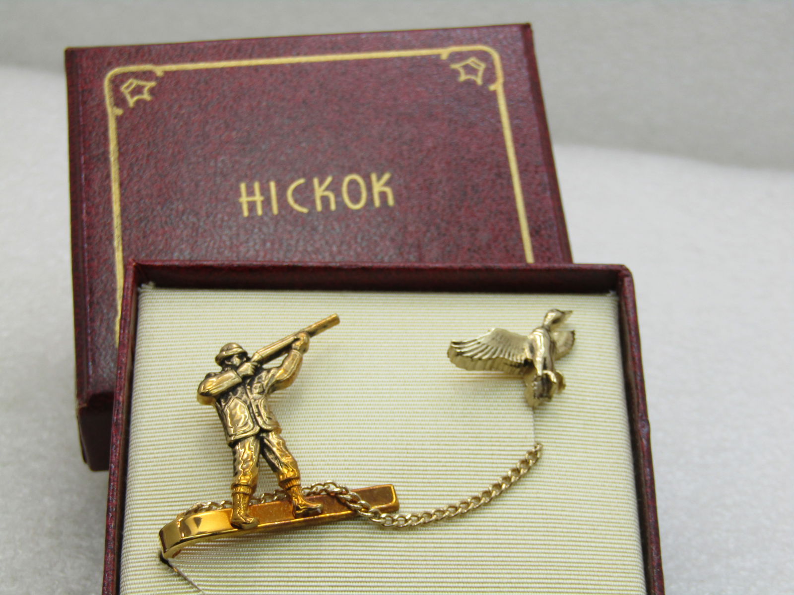Vintage Gold Tone Hickok Duck Hunter & Duck Tie Clasp & Tack Pin, Original Box: Vintage Gold Tone Hickok Duck Hunter & Duck Tie Clasp & Tack Pin, Original Box with enclosure card. Mid-Century. New Condition. 1.25" wide and tall on the hunter with chain and 1" duck. Very good