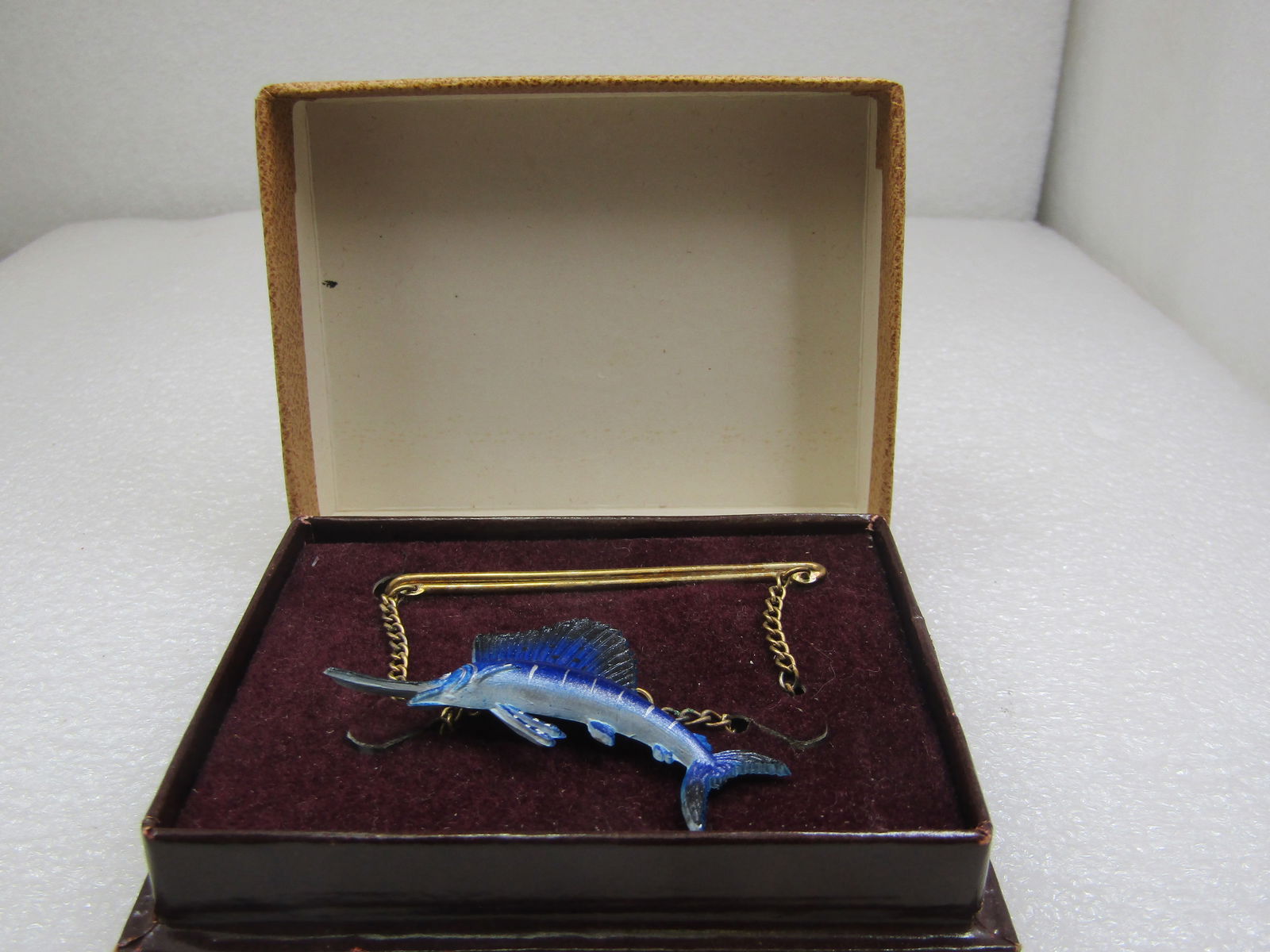 Vintage Sailfish Tie Bar by Wildlife Miniatures = in Box, 2.5": Vintage Sailfish Tie Bar by Wildlife Miniatures in Box, 2.5", Gold tone tie bar and chain with a plastic shimmery blue and silvery sailfish 2.25" wide and 1" tall. 1950's. Comes in original two-tone b