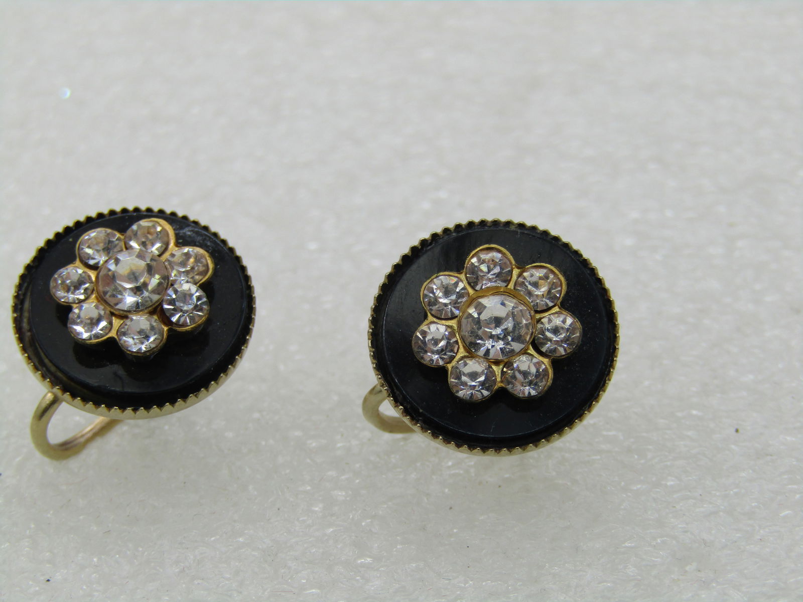 Vintage Black & Clear Rhinestone Blossom Earrings, Mid-Century, Screw Back: Vintage Black & Clear Rhinestone Earrings, Mid-Century, Screw Back. 5/8" base circle with pointed bezel and a center clear rhinestone blossom. The base piece looks like onyx but it is a black acrylic
