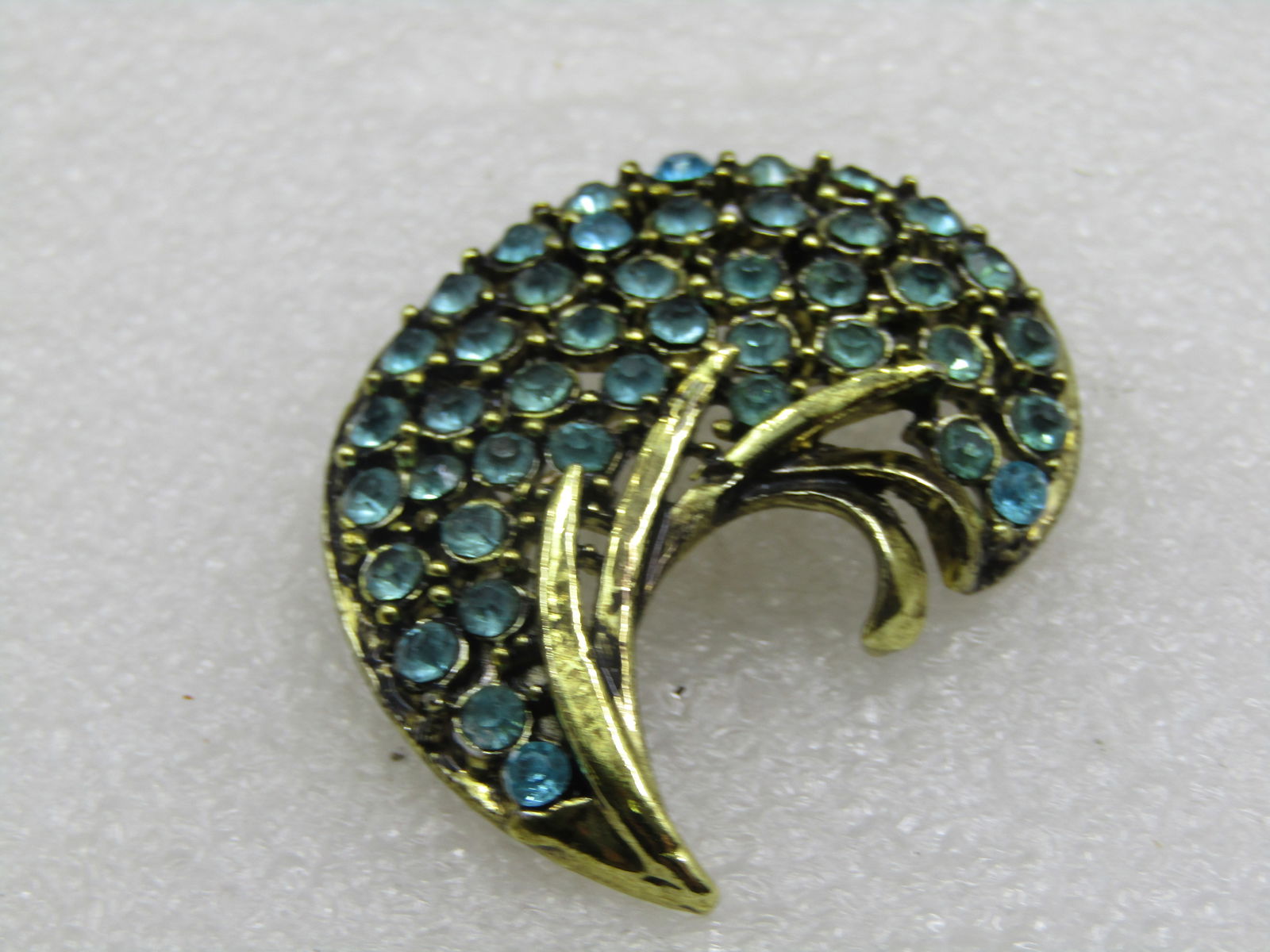 Vintage Aqua Rhinestone Crescent Brooch, 1.75" by 1.5". Gold tone. 1950's-1960's.: Vintage Aqua Rhinestone Crescent Brooch, 1.75" by 1.5". Gold tone. 1950's-1960's. It is not signed by the maker. Very good condition. (W92317.6 SS6617 J LD 2/21/22). Reserve: $30.00 Shipping: Domestic