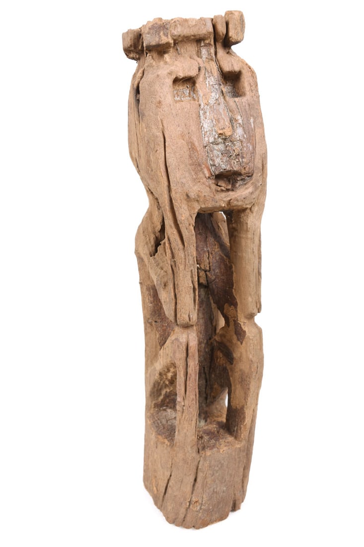 Ancestor Figure – Wood – Nepal: Great ancestor figure from Nepal. Wood, covered with red pigment, sitting with bended knees, prominent large head with rectangular deepened eye sockets and mouth opening, hole in the parting. 