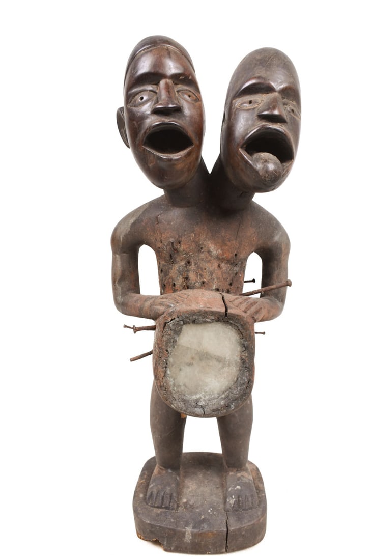 Ancestor Figure – Wood, Nail, glass – Yombe – Congo: Beautiful double headed Yombe ancestor figure from DR Congo. The wooden ancestor figure has a great patina of use, decorated with glass bilongo and nails. The 300,000 YOMBE people are artistically