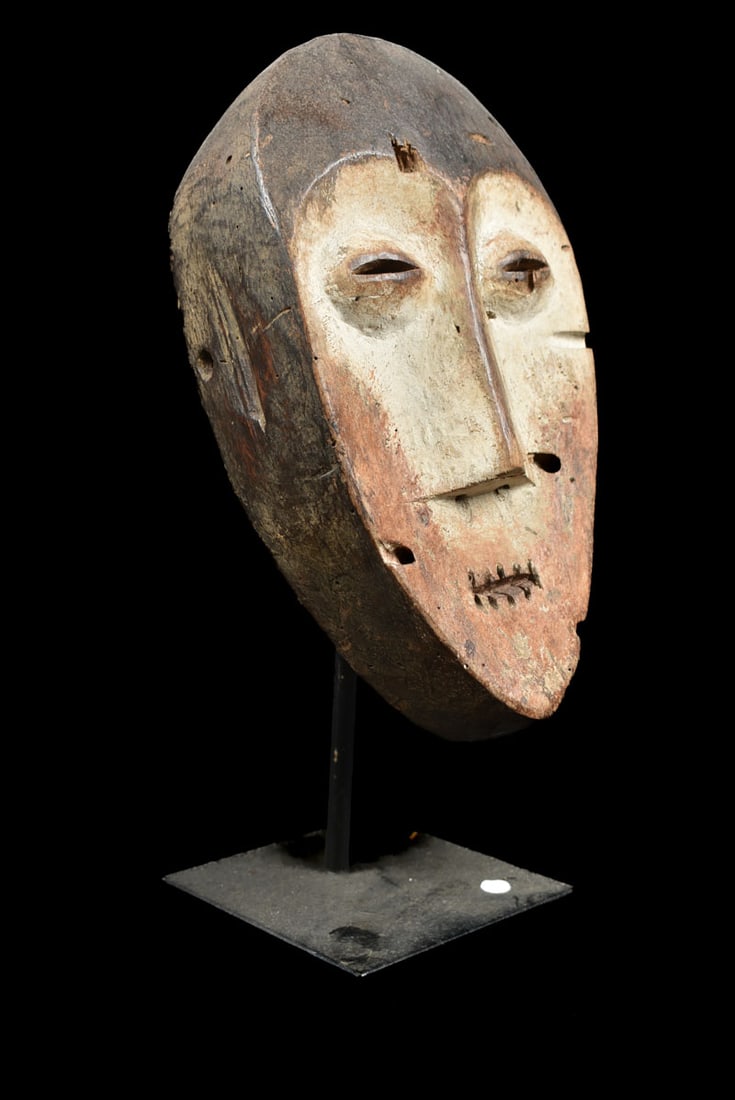 Mask – Wood – Lega – Congo: Lega Mask from Zaire or Congo. Wood with multi-layered patina. Remains of offerings, mica powder, kaolin. Condition: good with a beautiful aged patina due to tribal use. Covered in Pembe, white