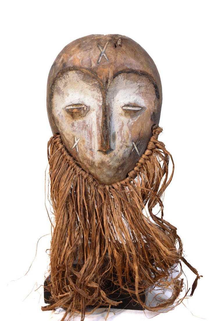 Mask – Wood, Raphia – Lega – Congo: Lovely Lega Mask from Zaire or Congo. Wood with multi-layered patina. Remains of offerings, mica powder, kaolin. Condition: good with a beautiful aged patina due to tribal use. Covered in Pembe,