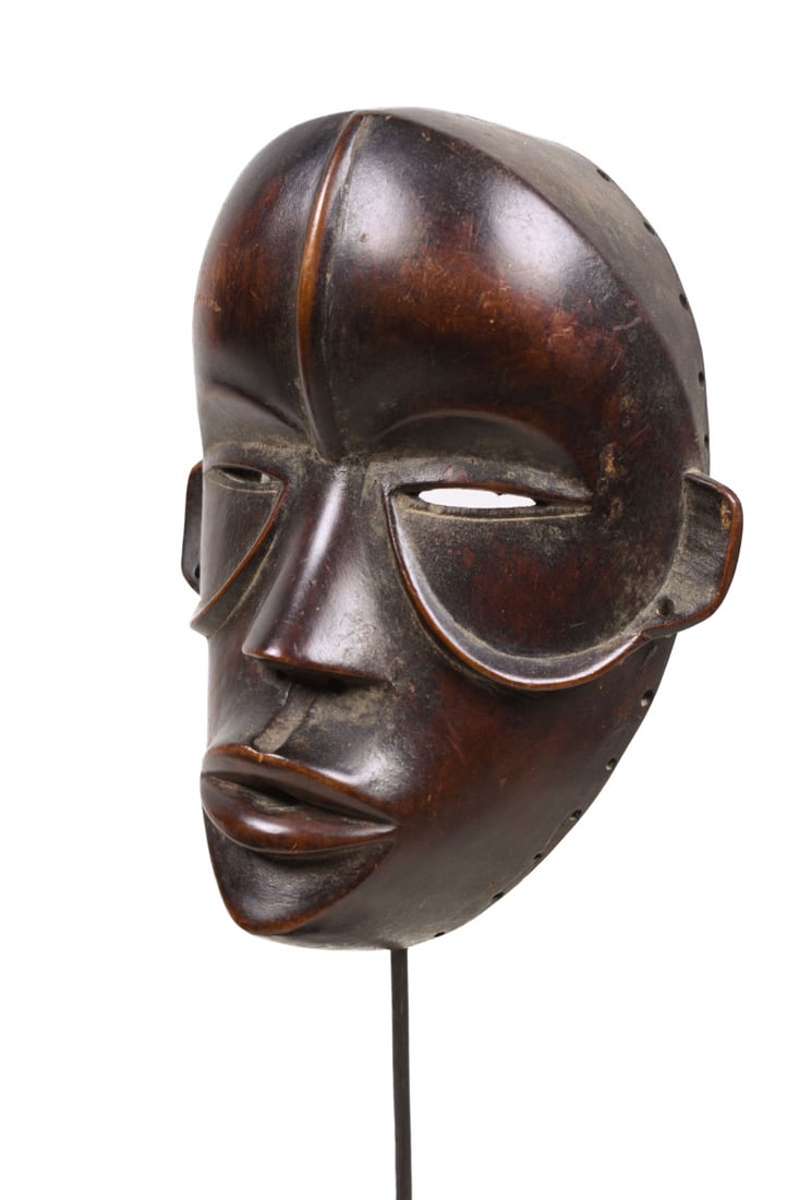 Mask – Wood – Dan – Ivory Coast: Authentic Dan mask in a very expressive design. The Dan style is quite evident, with slith eyes and large bulging mouth Good condition with a beautiful aged patina on the wood. The border between Cote
