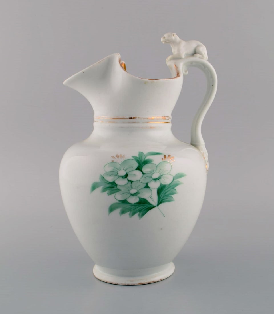 Antique Bing & Grøndahl chocolate jug in porcelain modeled with a lion on the handle.: Title: Antique Bing & Grøndahl chocolate jug in porcelain modeled with a lion on the handle. Hand-painted flowers and gold decoration. 1870s. Description: Antique Bing & Grøndahl chocolate j