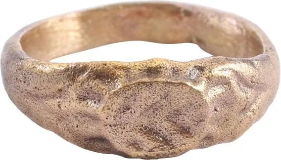 EARLY CHRISTIAN GIRL'S RING 7th-9th CENTURY, SIZE 3: 7th-9th Century. Rounded band of 2.9mm width, flared to the figured shoulders. Oval bezel inscribed with a chevron or fir tree motif. Size 3. Gilt bronze. Professionally refurbished with the 24karat