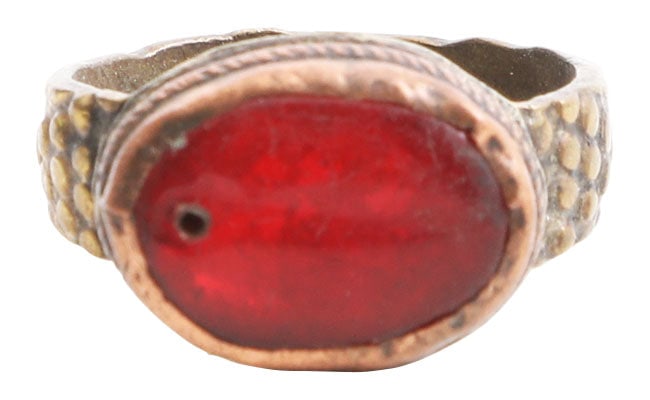 EASTERN EUROPEAN GYPSY RING, SIZE 9: 19th century. Yellow metal band, possibly low karat gold, 4.4mm, with scale motif shoulders. Roped medial bezel with red “stone” pierced one end . Good quality for these with a balance of