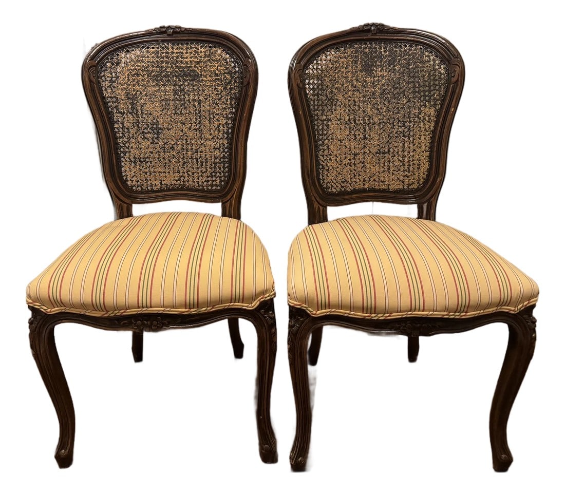 Pair of Late 19th-Century French Caned Side Chairs With Upholstered Seats: A charming pair of Louis XV-style caned side chairs featuring hand-carved walnut frames with delicate floral and foliate motifs along the crest rail, apron, and knees. The chairs rest on elegant
