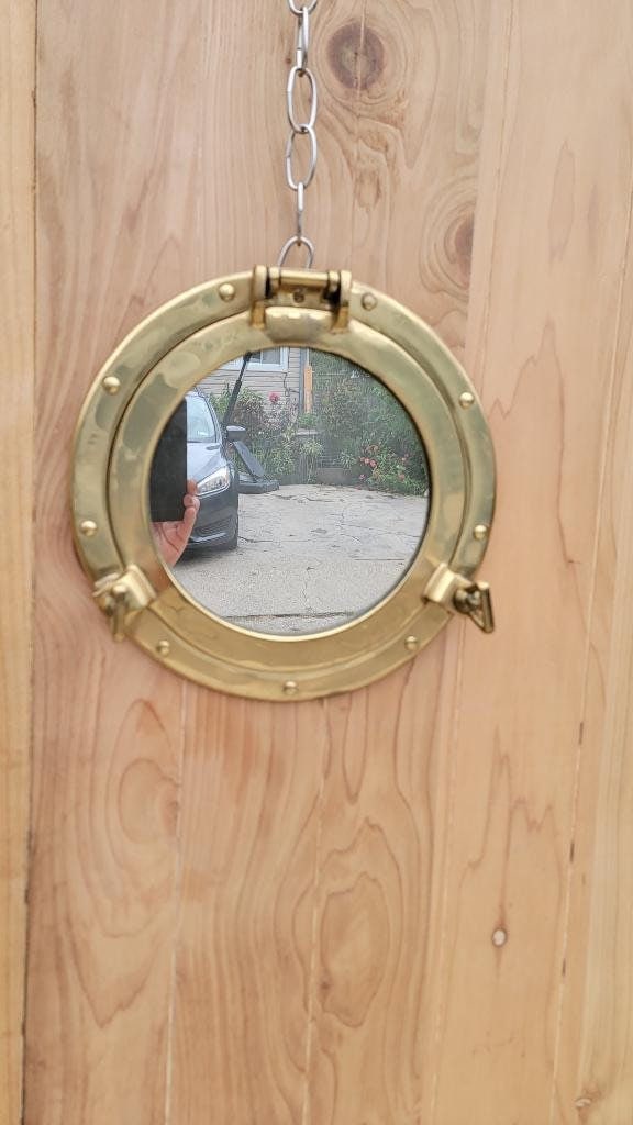Vintage Nautical Brass Porthole Mirror: Title: Vintage Nautical Brass Porthole Mirror Description: Vintage Nautical Brass Porthole Mirror Vintage round mirror in a brass porthole frame with cabinet door opening. It is a functional