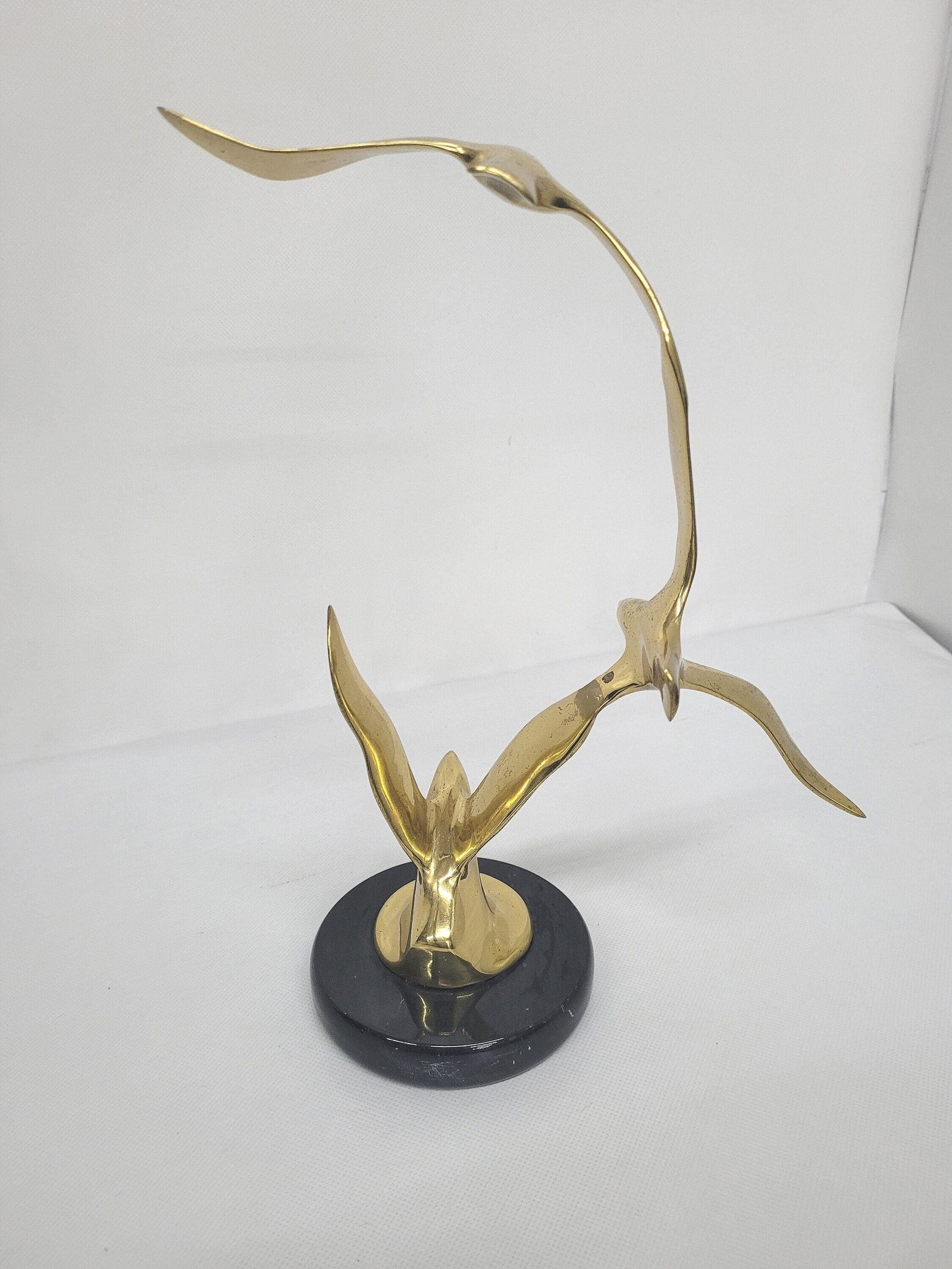 Modernist Brass Bird Sculpture on Black Marble Base Stylized Seabirds in Flight Mid Century Style: Title: Modernist Brass Bird Sculpture on Black Marble Base Stylized Seabirds in Flight Mid Century Style Decor 11" Description: Vintage from the 1970s Materials: Medium: Brass, Stone, Wood Width: 9