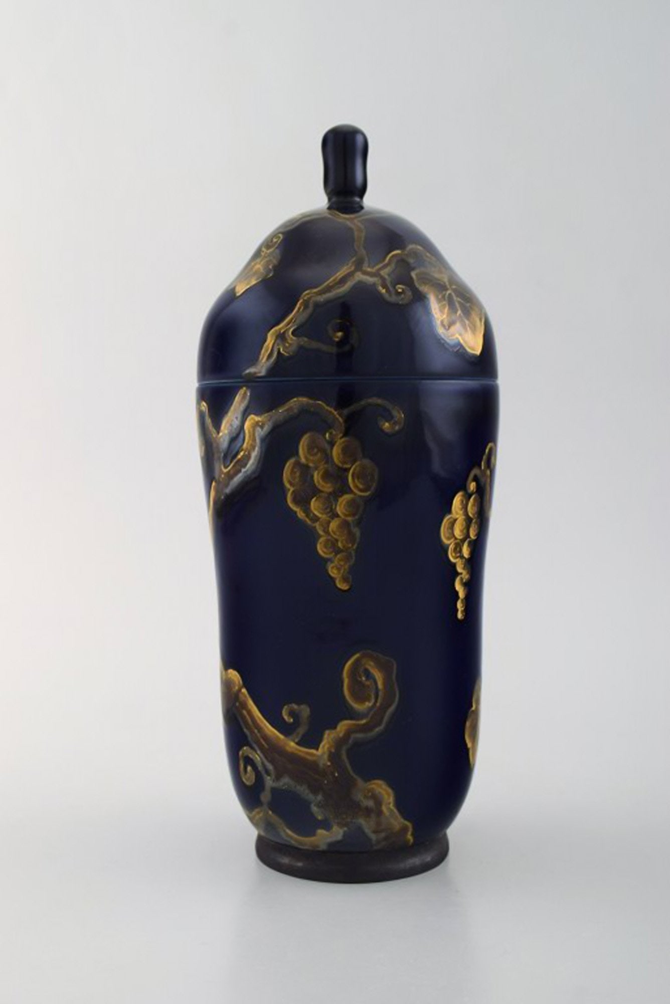 Karl Lindström and Nils Emil Lundström for Rörstrand. Lidded porcelain jar decorated: Title: Karl Lindström and Nils Emil Lundström for Rörstrand. Lidded porcelain jar decorated with grape vines in gold on beautiful dark blue base. Japanism, ca. 1920. Description: Karl