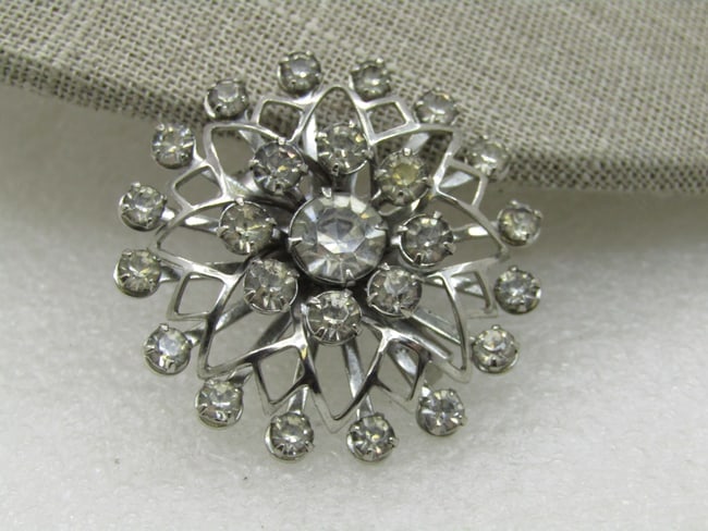 Vintage Rhinestone Brooch, 1960's, Silver Tone, 1.5": DescriptionVintage Rhinestone Brooch, 1960's, Silver Tone, 1.5" across. It has three tiers of round clear rhinestones with a recessed center larger rhinestone. Between the outer tier and the center ha