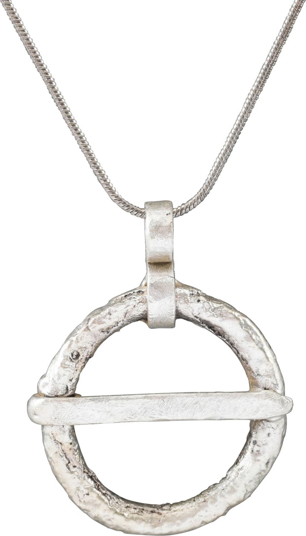 VIKING PROTECTIVE BROOCH PENDANT, 10th-11th CENTURY: Circular bronze, over 1” (1.10”) diameter. Circular section. Straight cross pin. The surface with textured from burial. Professionally conserved and the silver surface restored. On an 18&#