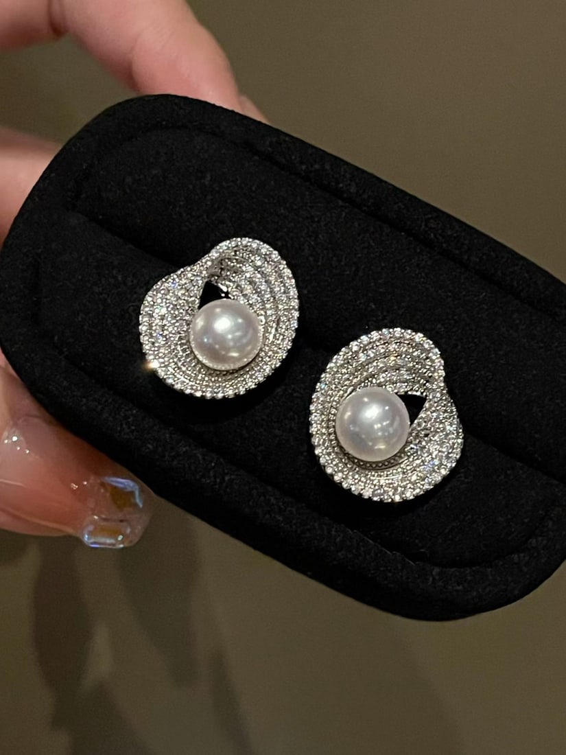 Natural freshwater pearl earrings: Title: Natural freshwater pearl earrings Description: These earrings feature a charming design, with intricately set cubic zirconia stones wrapping around in smooth elliptical curves, shimmering