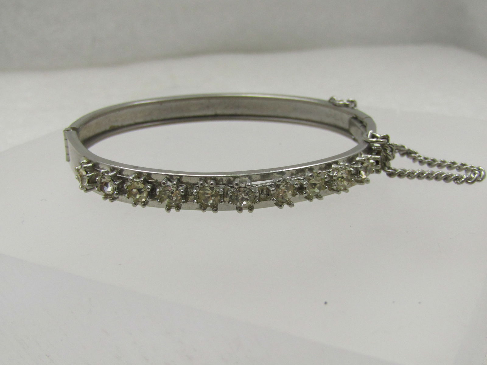 Vintage Rhinestone Hinged Bangle Bracelet, 6.75", Safety Chain: Title: Vintage Rhinestone Hinged Bangle Bracelet, 6.75", Safety Chain Description: Vintage Rhinestone Hinged Bangle Bracelet, 6.75", Safety Chain. Silver tone and appx. 6.5mm wide This has 11 appx. 4.