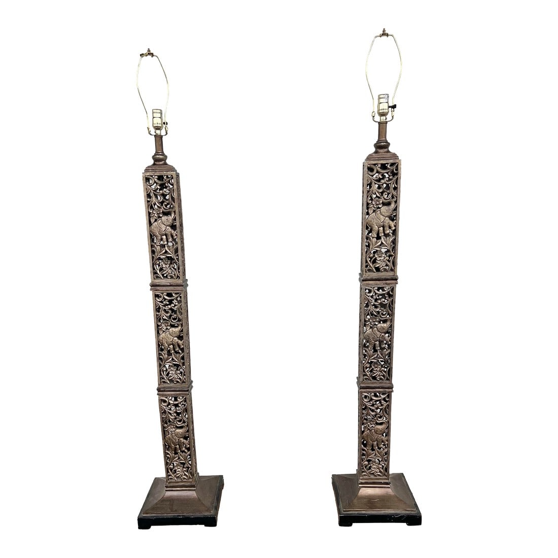 1990s Tall Floor Lamps With Elephants - a Pair: These lamps are tall, square columns with intricate, pierced carvings that prominently feature elephants. The design incorporates a traditional or safari theme and may be attributed to styles like