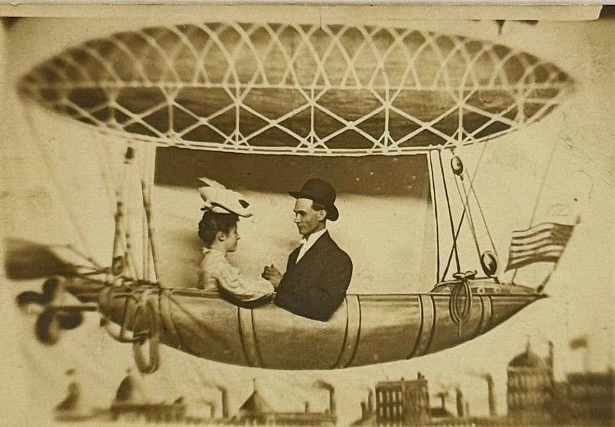 RPPC Real Photo Postcard Couple on Fantasy Flying Ship American Flag Circa 1900: Early real photo postcard of a couple holding hands on a studio fantasy airship with an American flag. Card is in very good shape and is postally unused. Signed - Miss Nellie Fagan - Livingston, Ala.