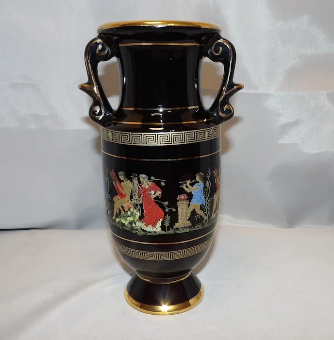 ADIS Double Handle Greek Urn Vase: Handmade in Greece, 24kt gold accents, black and gold porcelain. 8 ½” H. Shipping:Domestic: Flat-rate of $15.00 to anywhere within the contiguous U.S.International: Foreign shipping rates