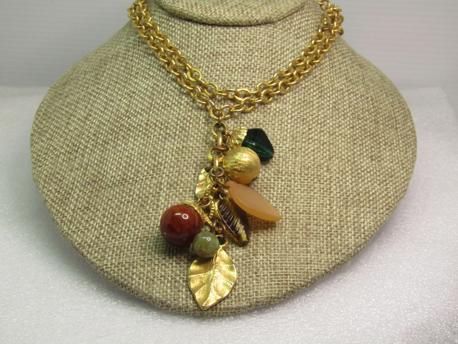 Vintage Leaf & Beaded Dangle Necklace, 32", 1980's: Vintage Leaf & Beaded Dangle Necklace, 32", 1980's. The dangle of gold tone leaves and a pale carved peach leaf and a yellow glass leaf hang frome the chain drop along with an appx. 15mm gold tone bea