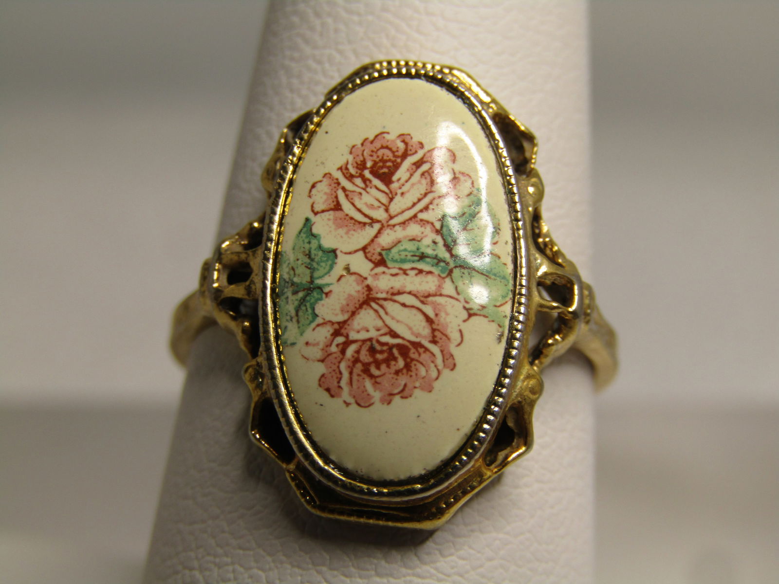 Vintage Double Rose Ring, Sz 8, Gold Tone, 1970's: Vintage Double Rose Ring, Sz 8, Gold Tone, 1970's. Oval Pink double rose ring with green leaves and open work frame. It is appx. 7/8" down the finger and 5/8" across the finger with white background.