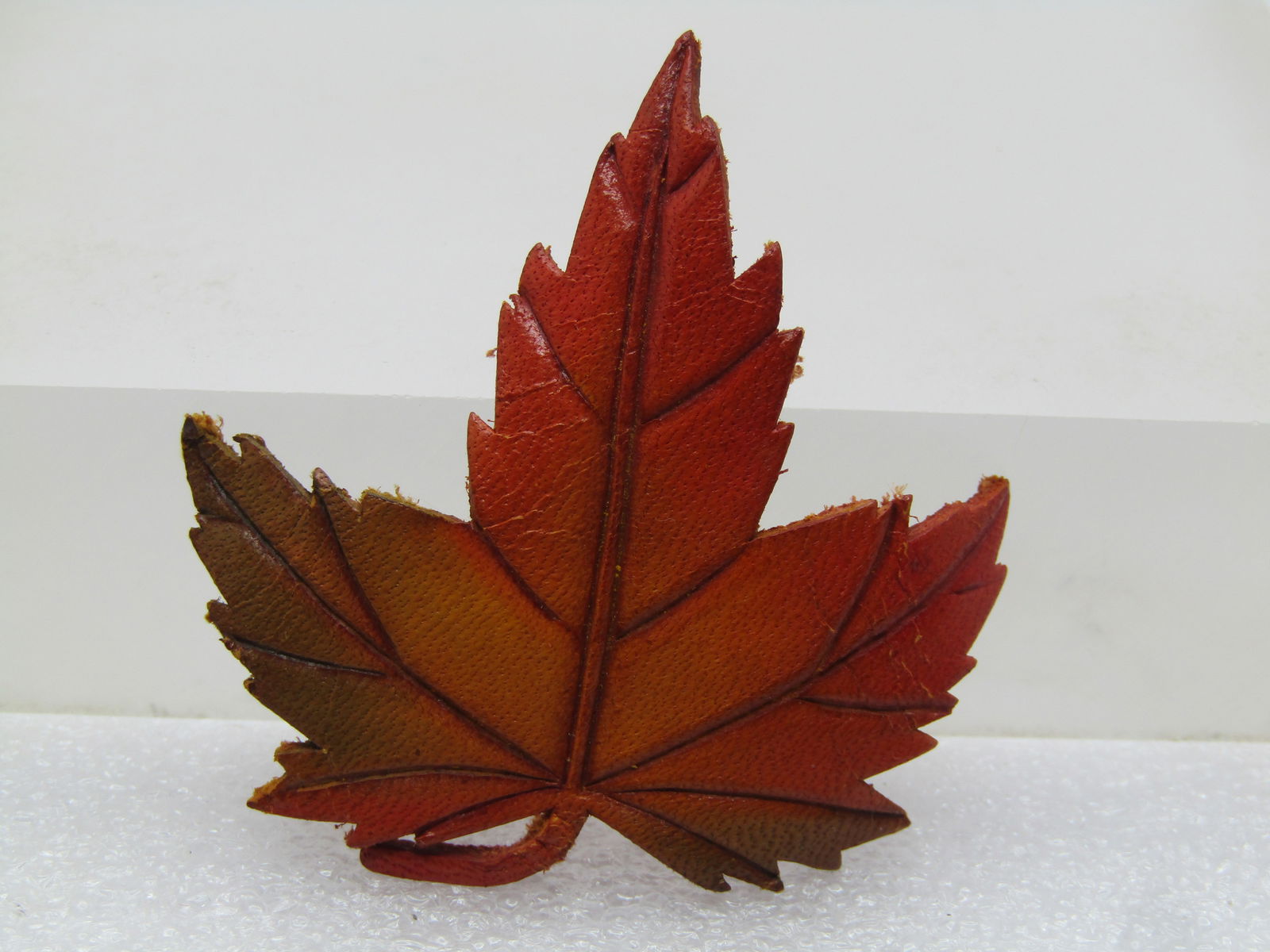 Vintage Leather Maple Leaf Brooch, 1980's-1990's, Canada: Vintage Leather Maple Leaf Brooch, 1980's-1990's, Canada. Natural leather with subtle shading in greens, and orange and yellow. It has a curved stem. it is appx. 2" tall and wide. It has nice