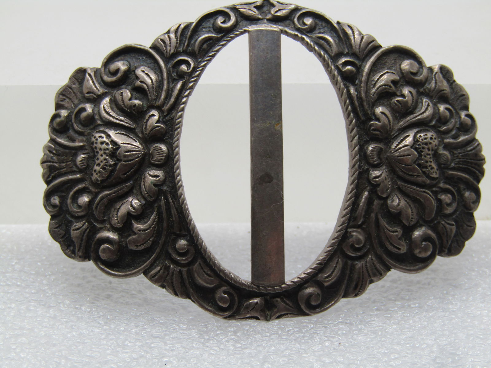Antique .800 Silver Sash Buckle/Slide, Floral Repousse 1800's-1920's: Antique .800 Silver Sash Buckle/Slide, Floral Repousse 1800's-1920's. Domed in the center with a single bar down the opening with raised scrolled and floral design. It is appx. 2.5" wide and 1.75"