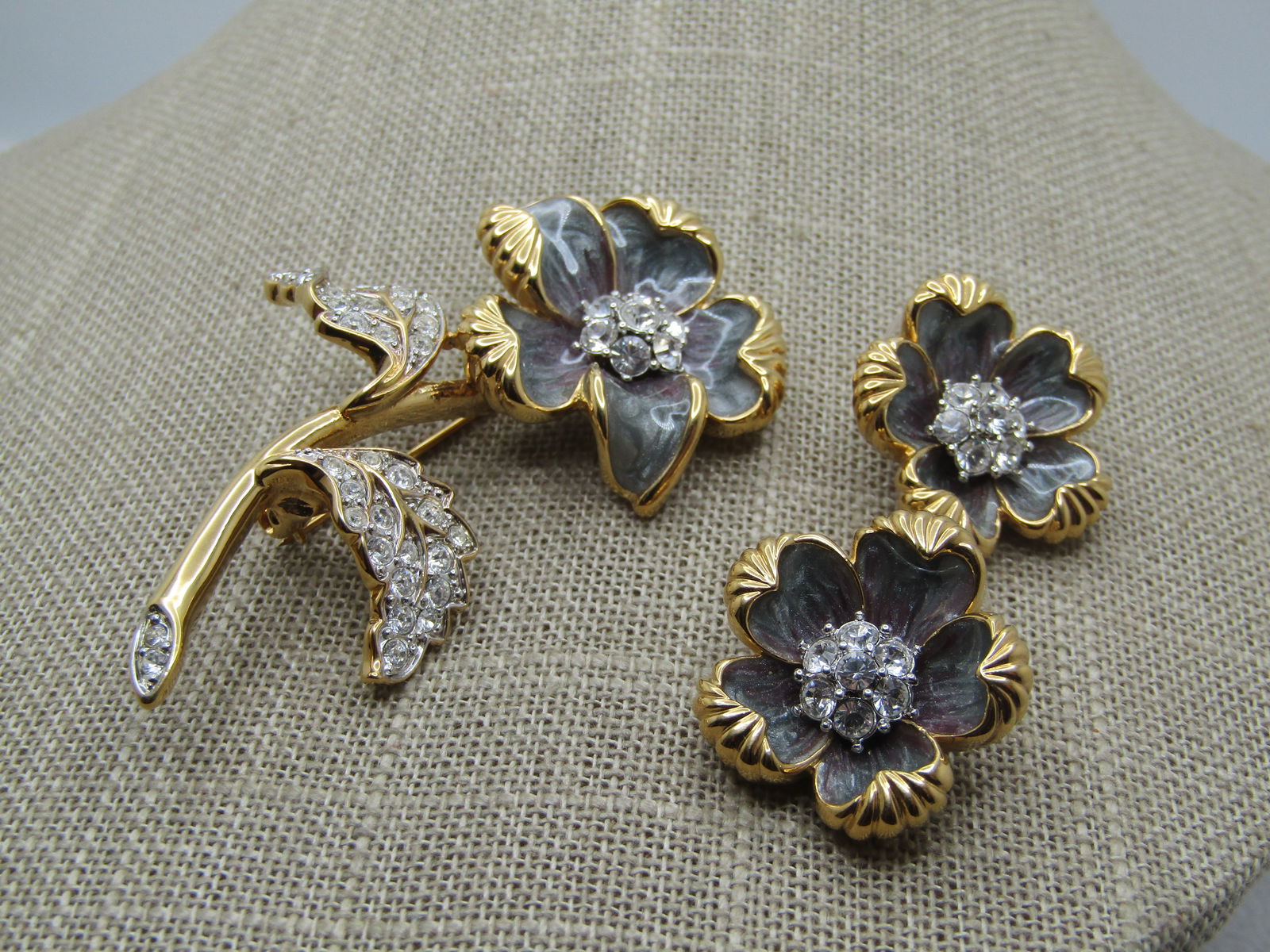 Nolan Miller Enameled Rhinestone Floral Brooch & Earrings Set, 1980's-1990's: Nolan Miller Enameled Rhinestone Floral Brooch & Earrings Set, 1980's-1990's. Enameled gray gold tone brooch and earrings set. The brooch has a rhinestone cluster in the center of the blossom with