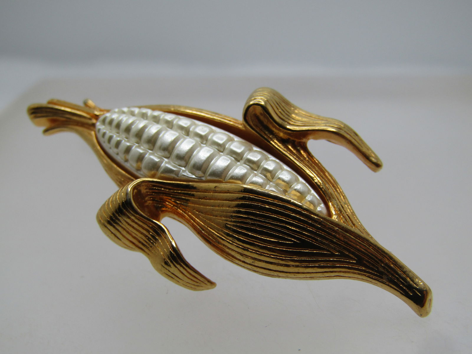 Vintage Corn-on-the-Cob Tack/Lapel Pin, 1970's-1980's: Vintage Corn-on-the-Cob Tack/Lapel Pin, 1970's-1980's. Gold tone ear of corn with white kernals molded in a plastic or acrylic. It is 2" tall and 1 wide. Brassy gold tone clutch. It is not signed by t
