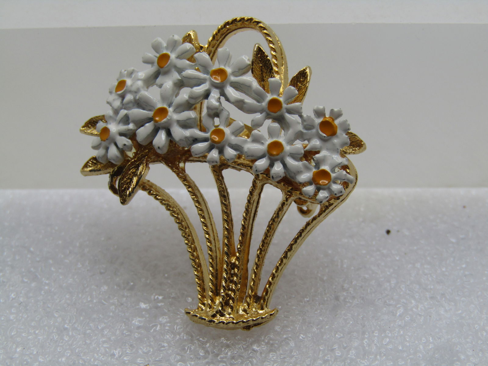 Vintage Enameled Daisy Basket Brooch, 1960's: Vintage Enameled Daisy Basket Brooch, 1960's. Gold tone basket with textured finish that is fileld with white and yellow enameled daisy blossoms with a few gold tone leaves off to the left side. It