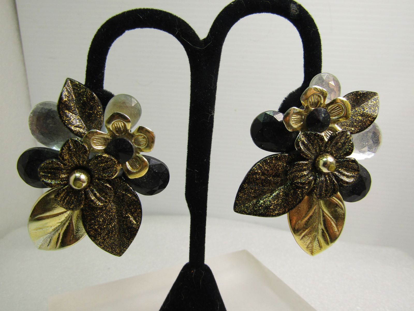 Vintage 1980's Floral Clip Earrings, Big and Bold: Vintage 1980's Floral Clip Earrings, Big and Bold. Gold tone, silver tone and black with gold glittery accents on this blossom and leaf design with clear faceted and black faceted acryklic stones. 