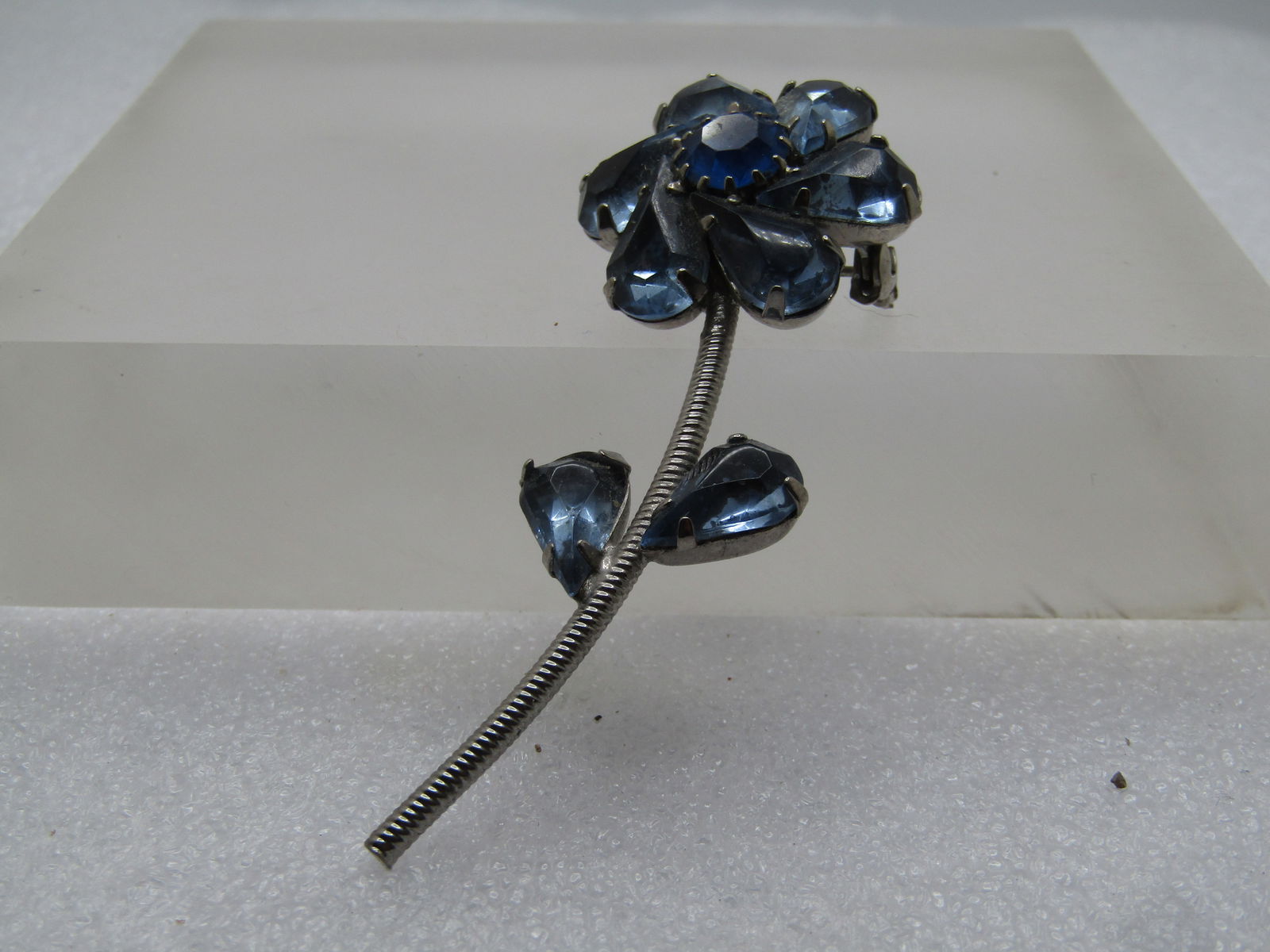 Vintage Blue Rhinestone Floral Stem Brooch, 1960's: Vintage Blue Rhinestone Floral Stem Brooch, 1960's. It is silver tone and 2.75" tall and 1" wide at the blossom Locking clasp. The blossom is a spiral of pear-shaped baby blue rhinestones that