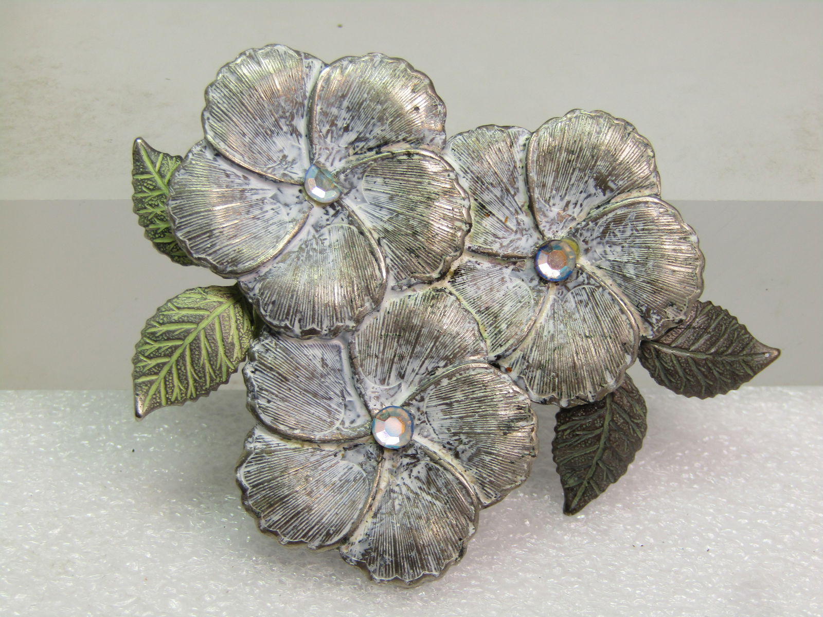 Vintage Enameled Triple Blossom Brooch, 1980's-1990's, AB Centers: Vintage Enameled Triple Blossom Brooch, 1980's-1990's, AB Centers. Metal base which appears to be a silver tone, with a matte green finish over the leaves and white over the blossom that is done in