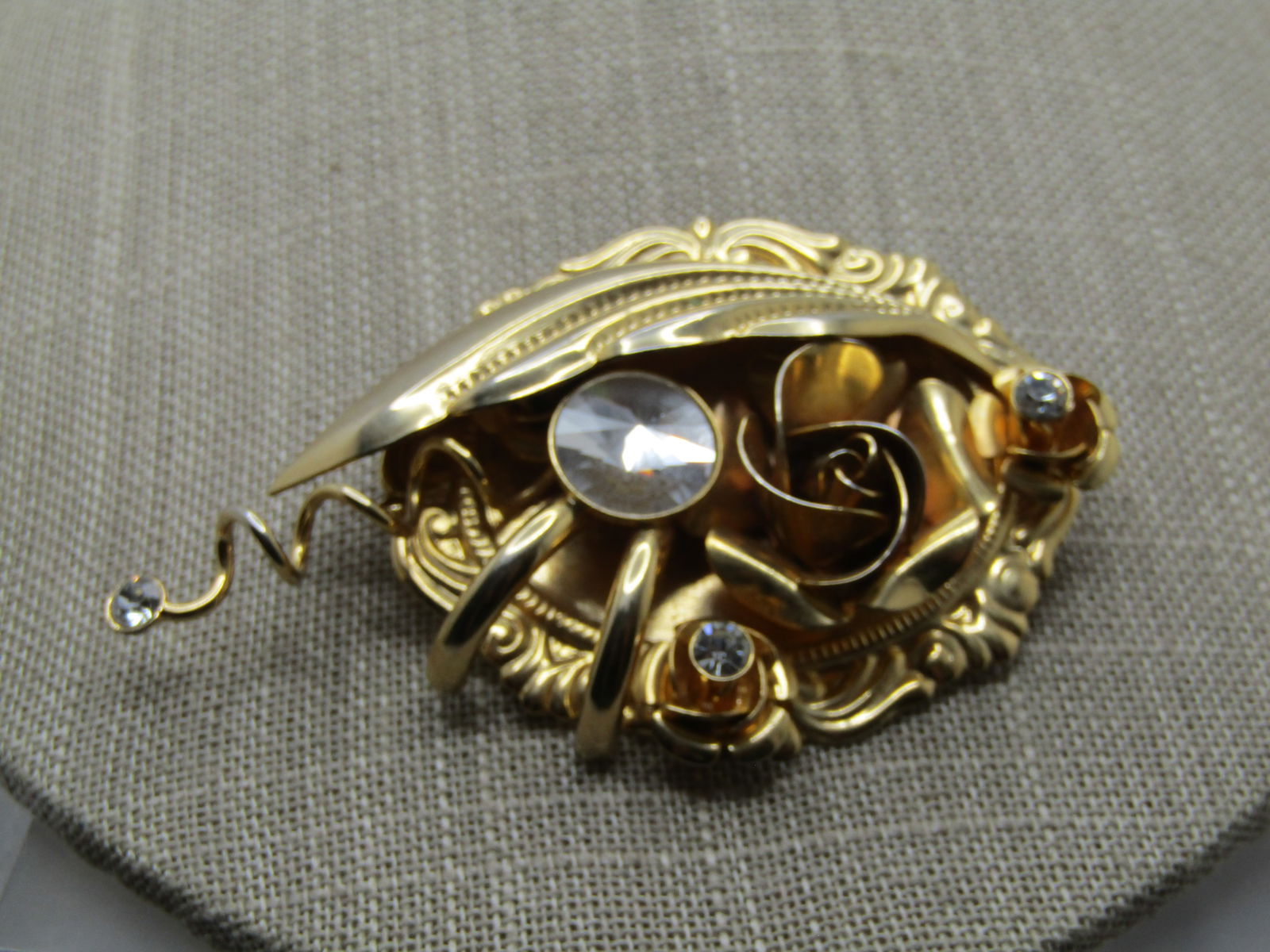 Vintage Floral and RS Statement Brooch, 1970's-1980's: Vintage Floral and RS Statement Brooch, 1970's-1980's. The base has a scrolled frame with two smaller rose bud accents with a clear rhinestone in each as well as a larger rose blossom more tot he cent