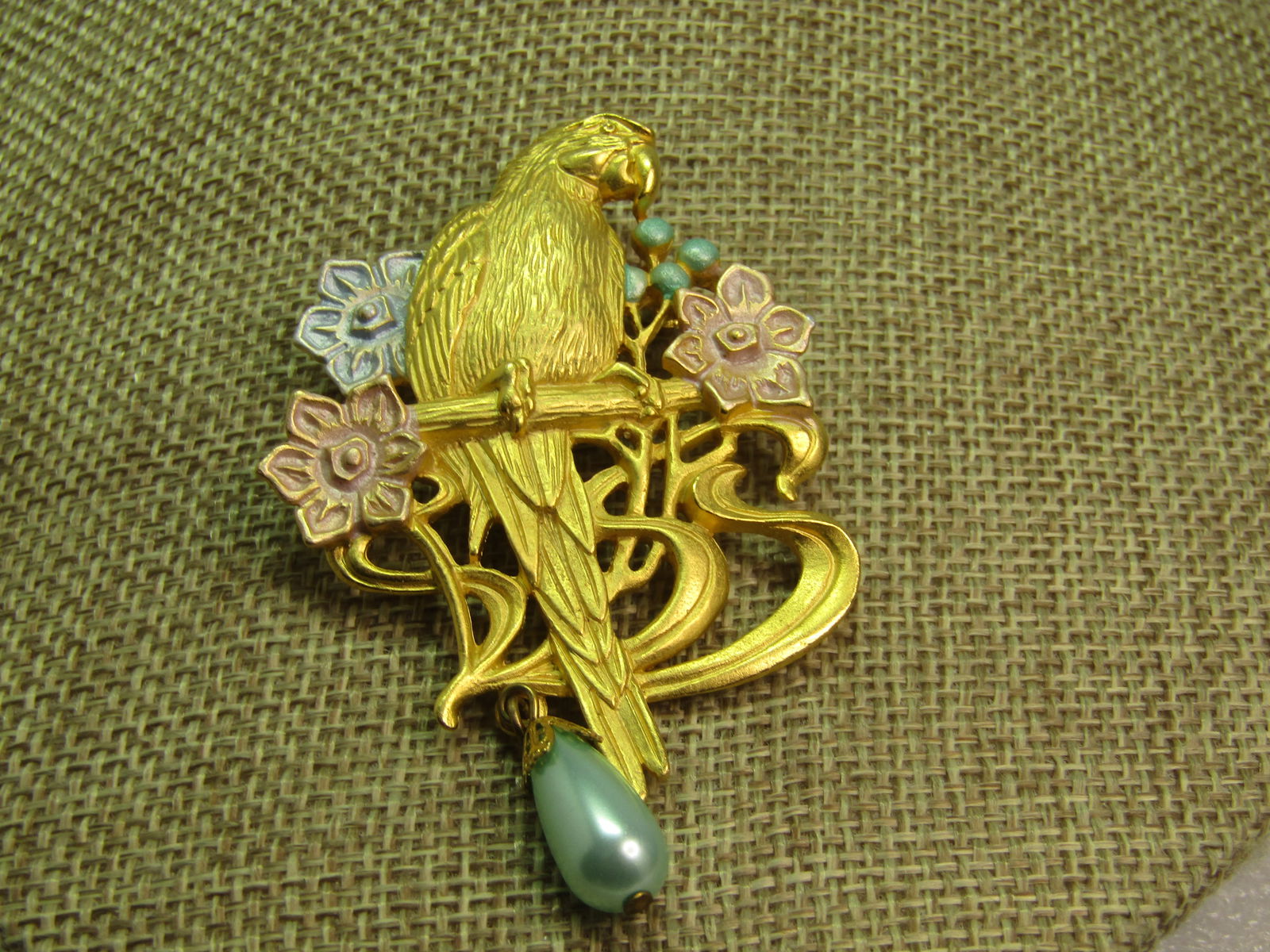 Vintage Parrot Pastel Floral Brooch, Faux Pearl Drop, Signed JJ, 1980's: Vintage Parrot Pastel Floral Brooch, Faux Pearl Drop, Signed JJ, 1980's. Gold tone with pastel lavender and blue blossoms and a dangling aqua faux pearl. The parrot is sitting on a perch with curved a