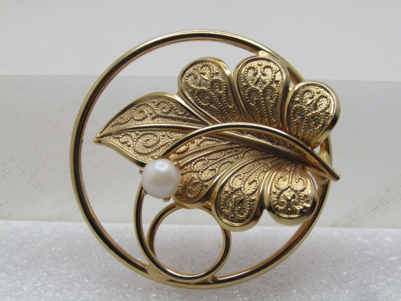 Vintage Faux Pearl & Leaf Brooch, Cirl with Coil, 1960's-1970's: Vintage Faux Pearl & Leaf Brooch, Cirl with Coil, 1960's-1970's. Gold tone with a textured leaf with a lower center and a coil passing over and wrapping in a circle at the right side of the round fram