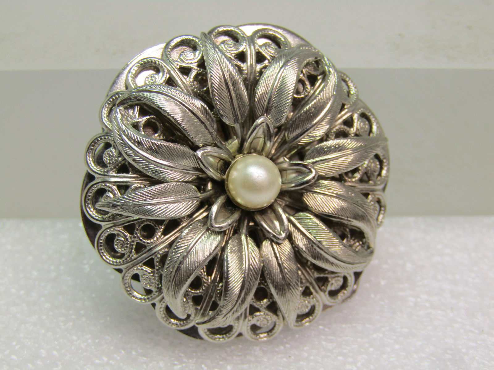 Vintage Filigree Blossom Scarf Clip, 1960's-1970's: Vintage Filigree Blossom Scarf Clip, 1960's-1970's. Very strong hinged clip. It has a faux pearl in center with textured petals and a filigree domed base. It is appx. 1.5" across, just under. It