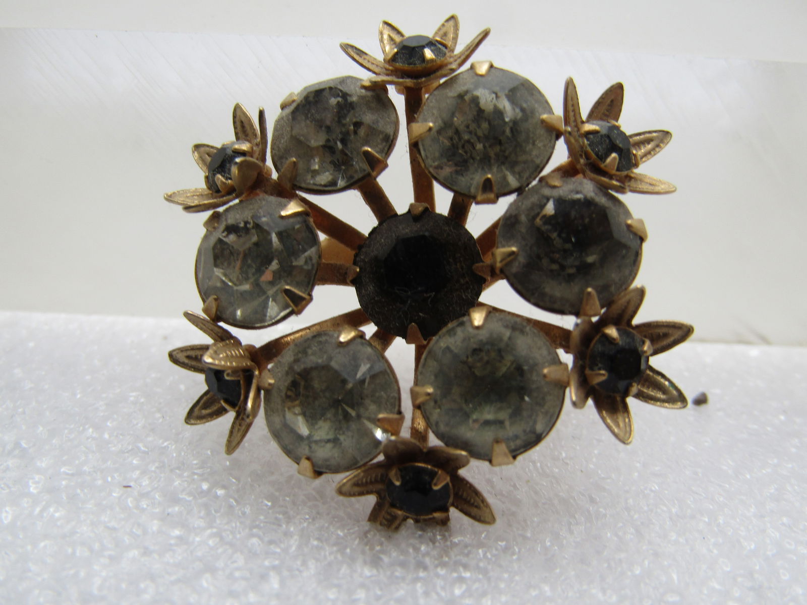 Vintage Black & Clear Rhinestone Floral Brooch, 1940's: Vintage Black & Clear Rhinestone Floral Brooch, 1940's. Gold tone with a center recessed black rhinestone tha is appx. 8mm wide with rays of gold tone metal coming up and each holding an appx. 8mm