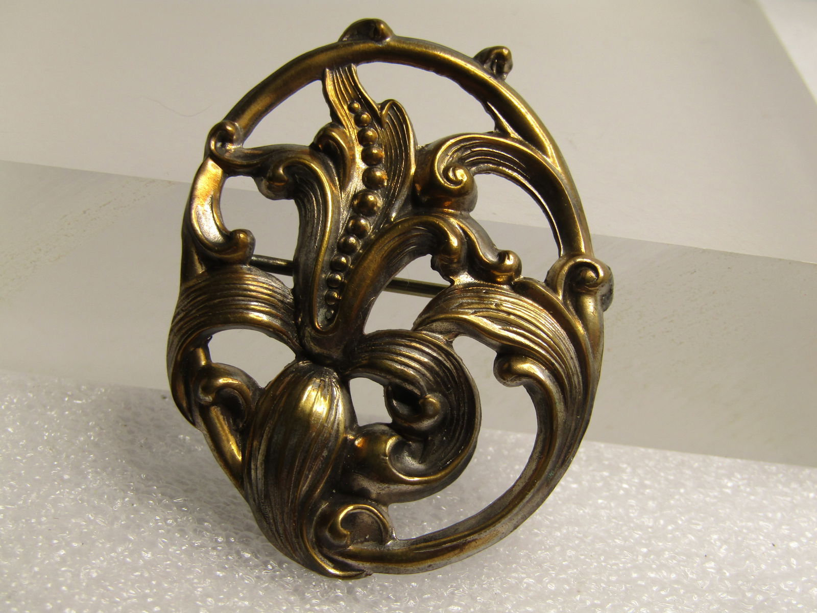 Vintage Art Nouveau Floral Brooch, Late 1930's-1940's: Vintage Art Nouveau Floral Brooch, Late 1930's-1940's. Pressed brass tone metal oval brooch with scrolled leaves around and framing the brooch with a center blossom and more curled and curved leaves