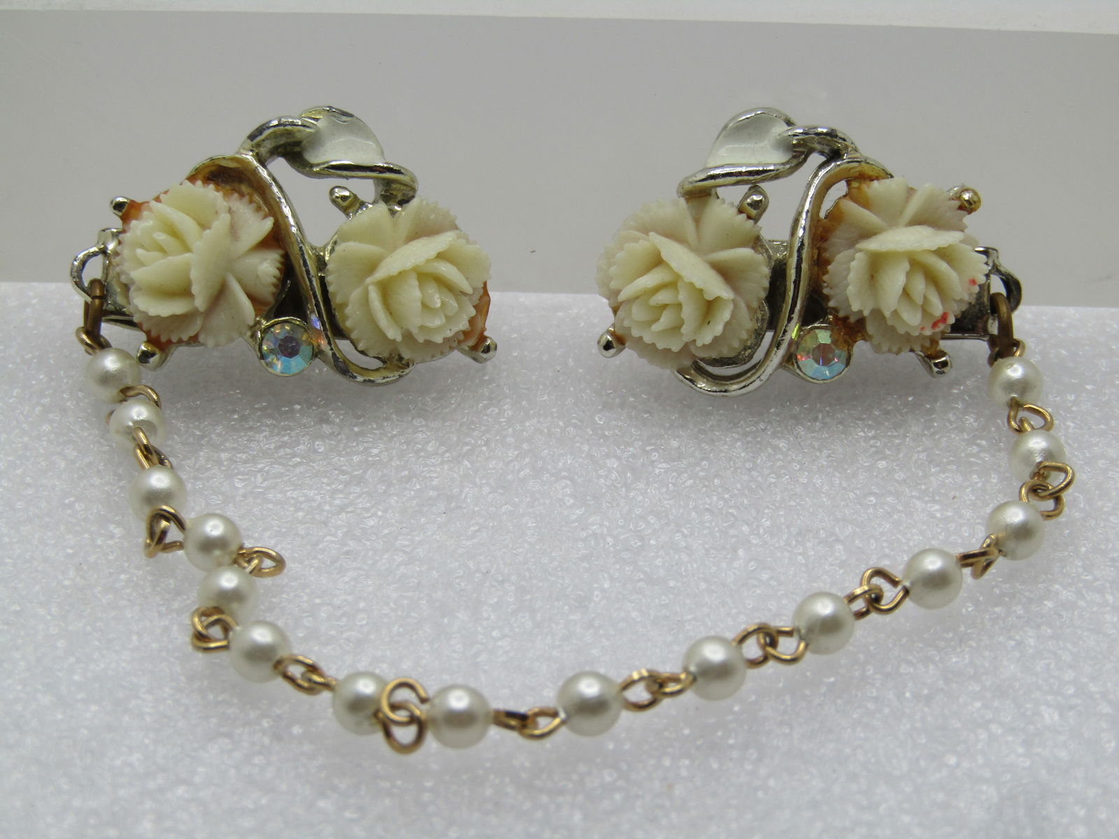 Vintage White Rose Faux Pearl Sweater Guard, 1950's-1960's, 7.5", AB Rhinestones: Vintage White Rose Faux Pearl Sweater Guard, 1950's-1960's, 7.5", AB Rhinestones. White enameled leaves with two molded (faux carved) white roses and an AB rhinestone on each clip. There is a 5.5"