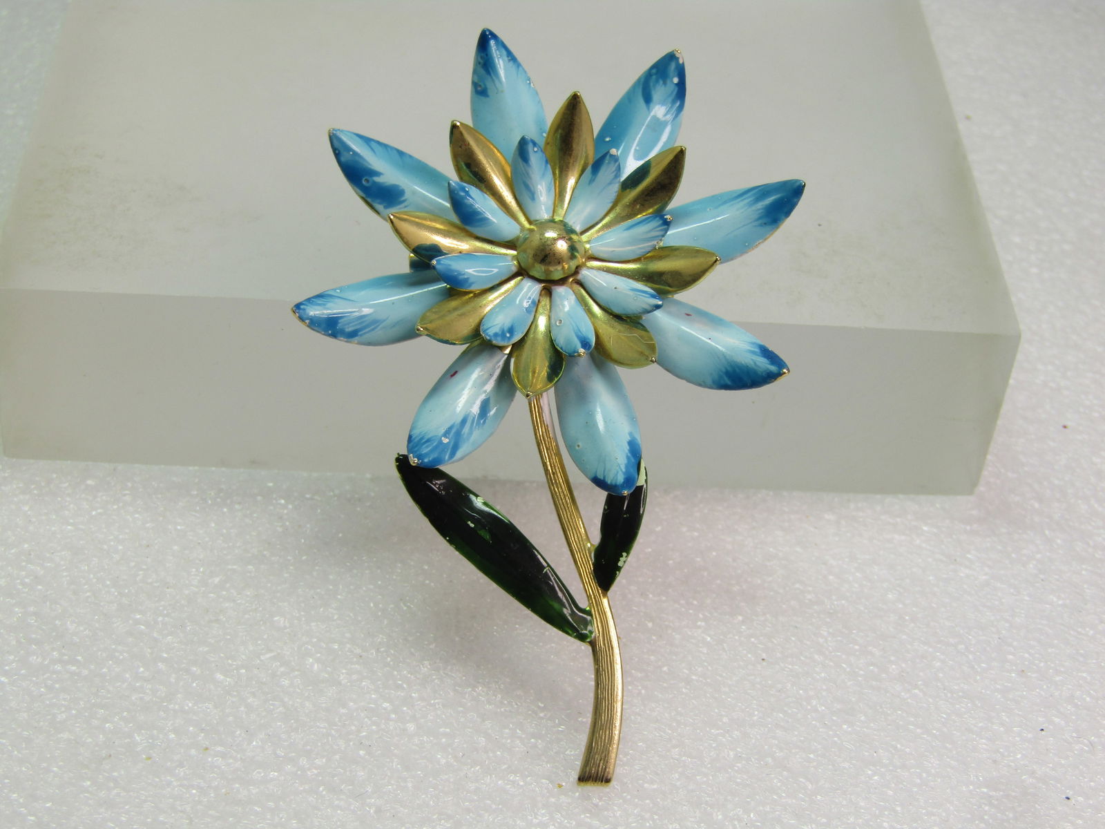 Vintage Blue/White Enameled Floral Brooch, Long Stem, 1940's-1960's: Vintage Blue/White Enameled Floral Brooch, Long Stem, 1940's-1960's. This also has two green leaves and a textured gold tone stem thta is slightly curved. The petals are pointed and curve upward in a