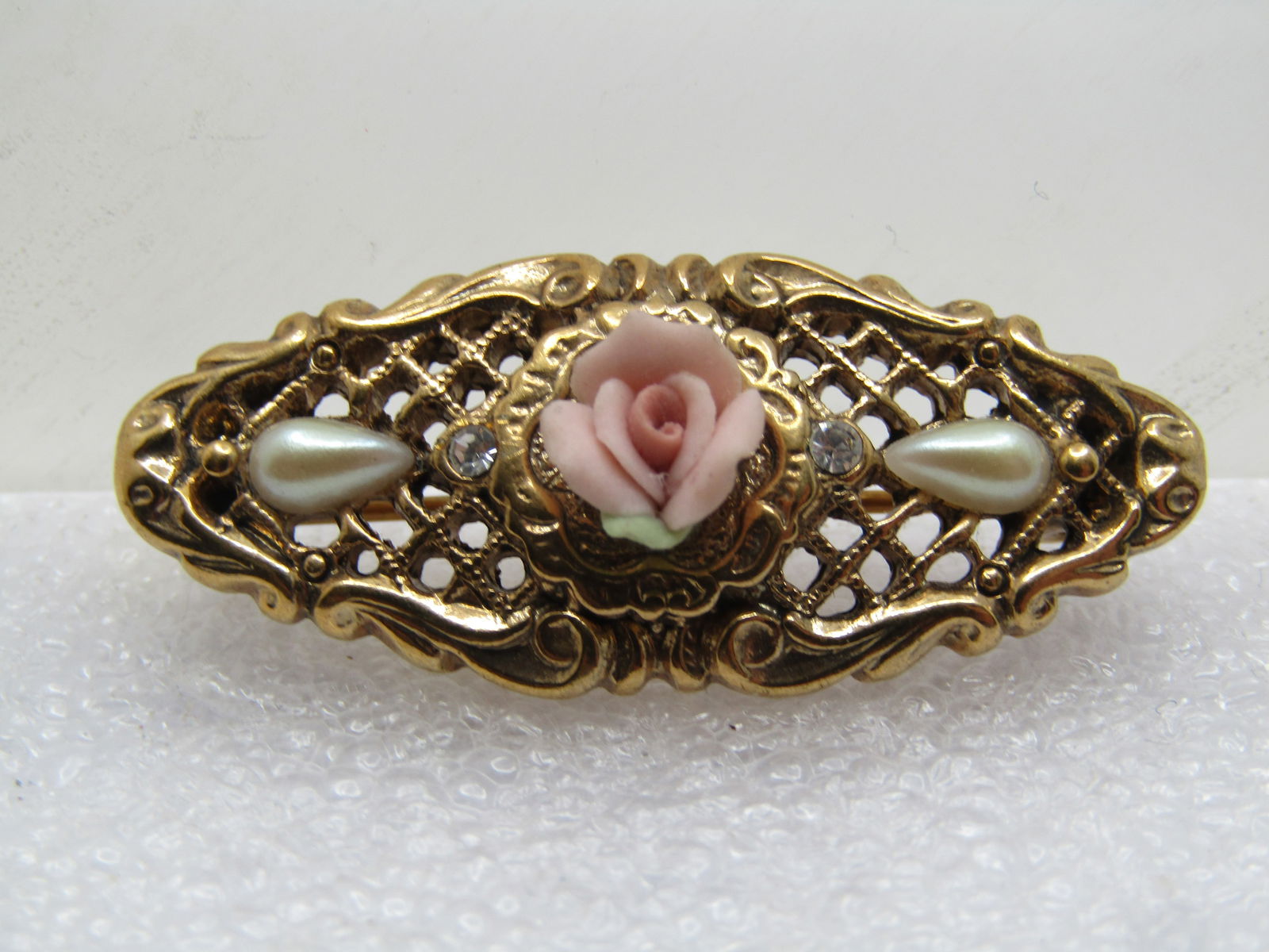 Vintage Porcelain Rose, Faux Pearl Brooch, 1980's-1990's: Vintage Porcelain Rose, Faux Pearl Brooch, 1980's-1990's. oval open grid textured brooch with faux pearls and a center raised orcelain rose with two rhinestones. This is 1928 I believe by looking at t